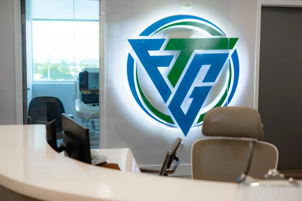 Reception desk and illuminated FTG Ortho logo at the Aventura, FL orthopedic clinic