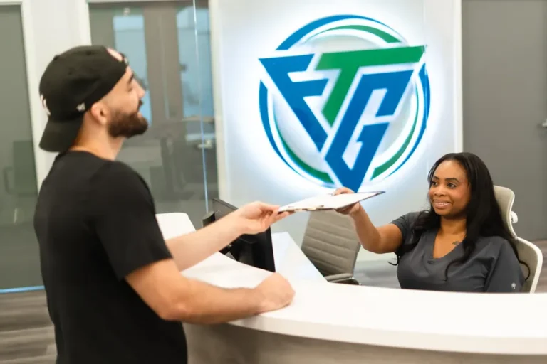 Patient handing completed paperwork to the FTG Ortho front desk in Aventura